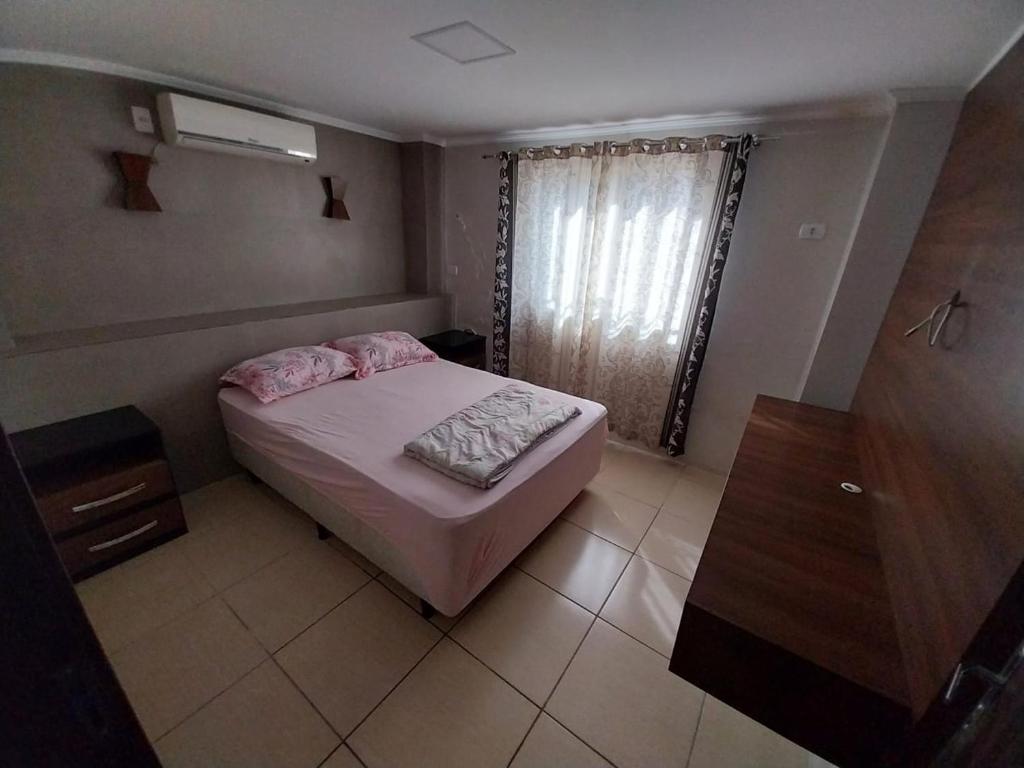 a small bedroom with a bed and a window at Casa em Blumenau Oktoberfest e demais eventos até 13 pessoas in Blumenau