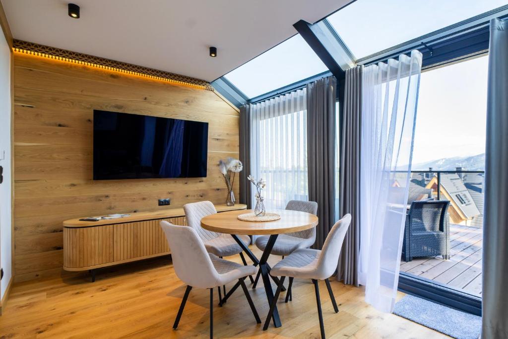 una sala da pranzo con tavolo, sedie e TV di Apartament Magiczne Podhale by Apart Concept Podhale a Kościelisko