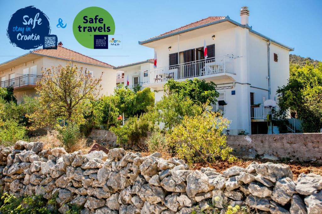 une maison avec un mur en pierre devant elle dans l'établissement Apartments Nemo, à Vinišće