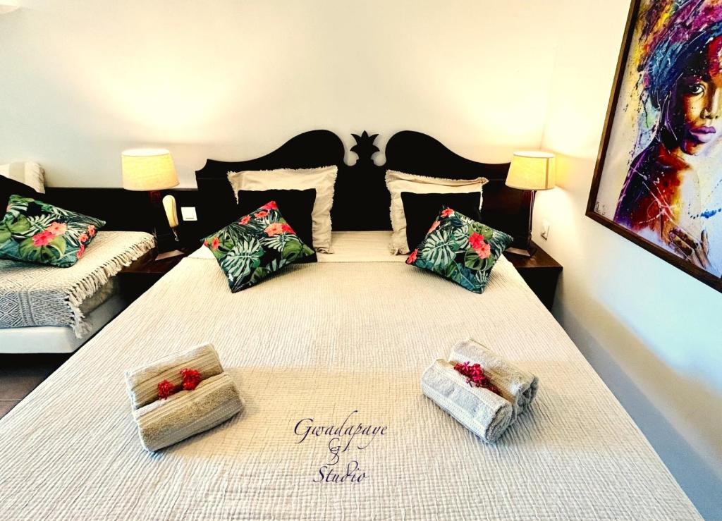 um quarto com uma cama grande e 2 almofadas em Vue Exclusive Mer et Volcan, Village Vacances avec Plage et Piscine, Les Gwadastudios em Sainte-Anne
