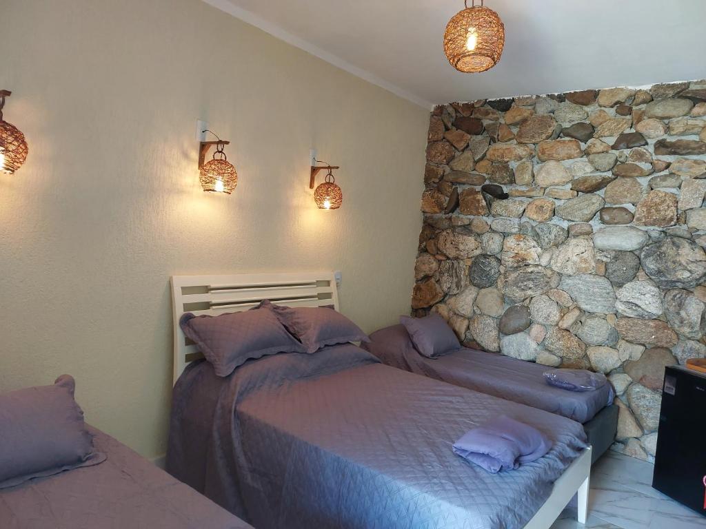 ein Schlafzimmer mit einem Bett und einer Steinwand in der Unterkunft Casa das Pedras in Caraguatatuba