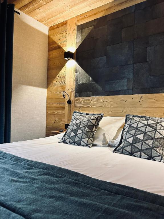 ein Schlafzimmer mit einem großen Bett und einer Holzwand in der Unterkunft Hameau des Prodains - Hôtel in Morzine