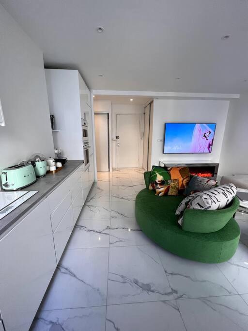 un salon avec un canapé vert et une télévision à écran plat dans l'établissement Promenade Des Anglais 20m, à Nice