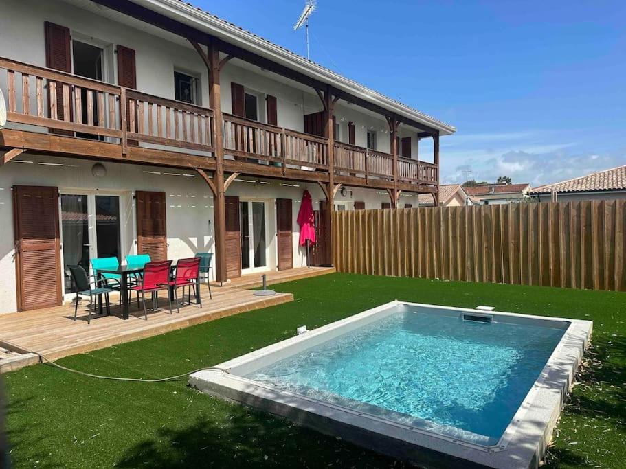 une cour arrière avec une piscine et une maison dans l'établissement Maison 100m2 4 chambres avec piscine jardin paysage, à Gujan-Mestras