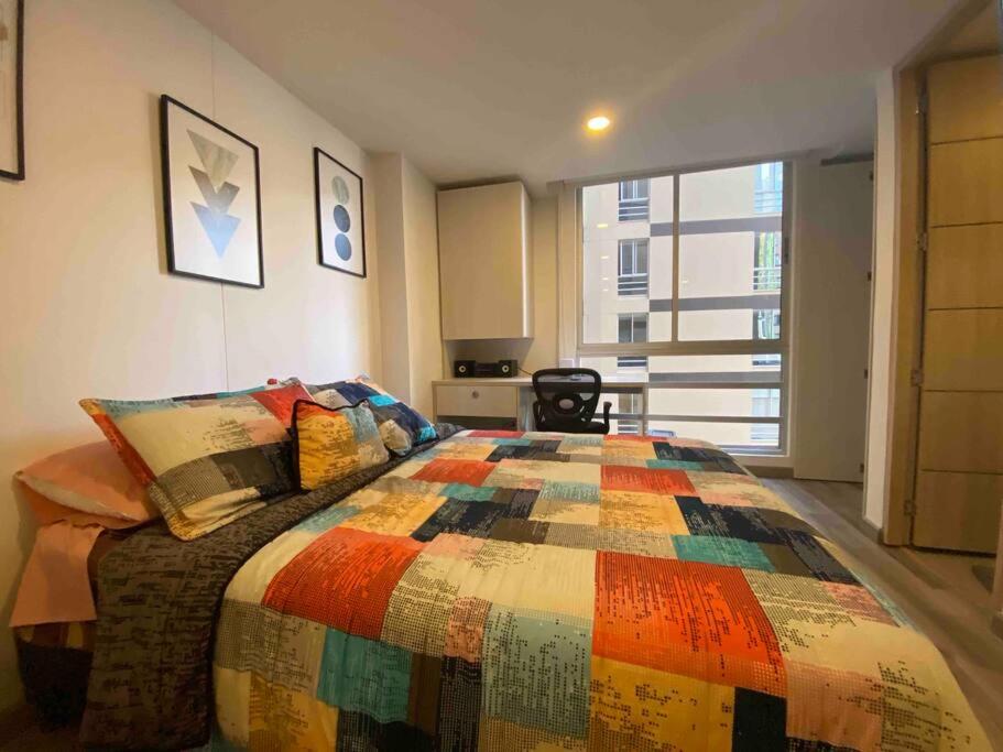a bedroom with a colorful quilt on a bed at Apartaestudio Centro Historico Bogota in Bogotá