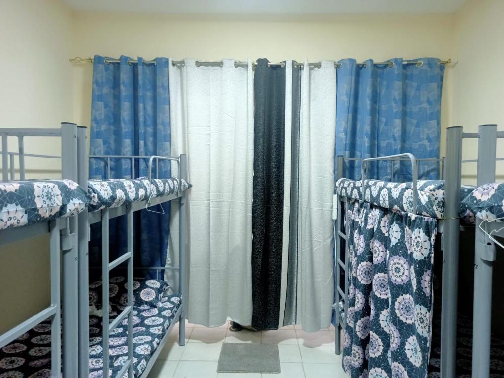 two bunk beds in a room with blue curtains at The Sky Hosteller Dubai in Dubai