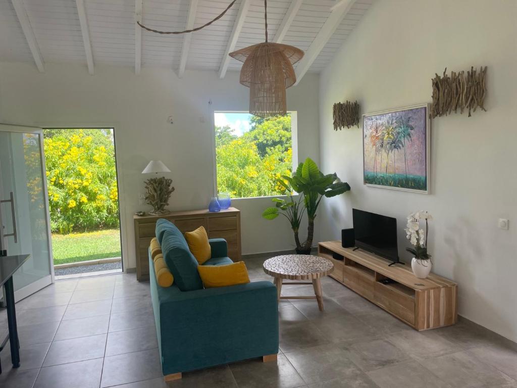 a living room with a blue couch and a tv at Villa Tropic' Al. Piscine privée. Cuve à eau in Saint-François