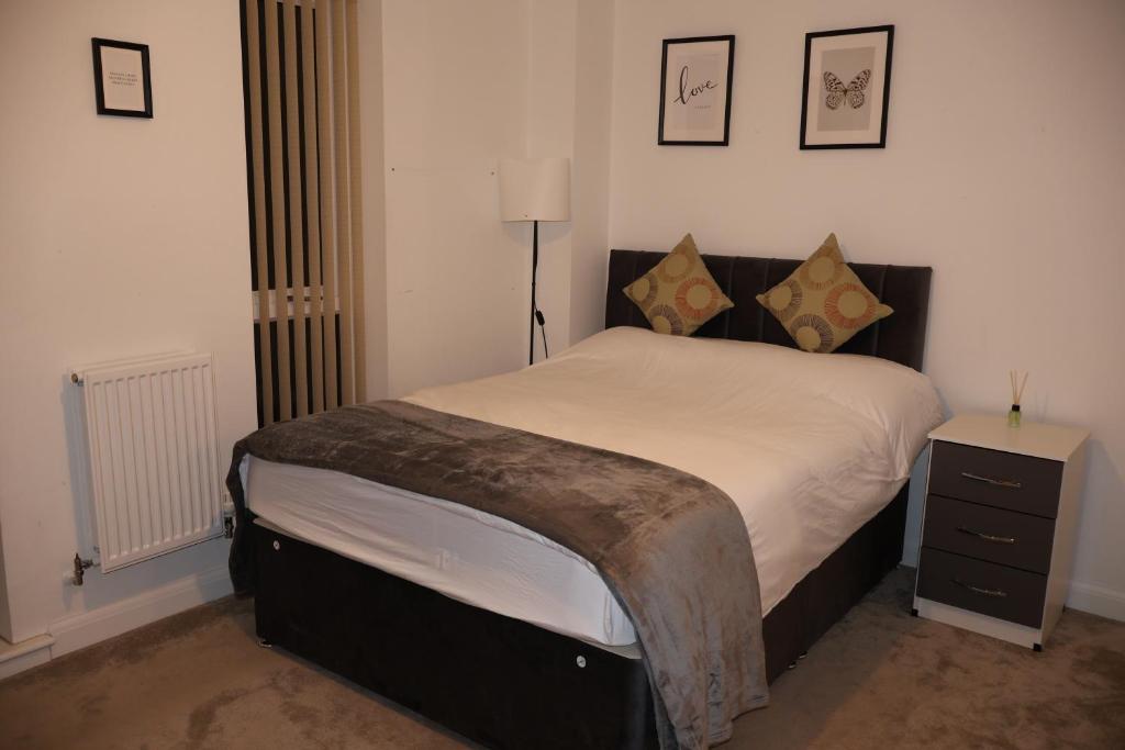 a bedroom with a large bed with a nightstand and pictures on the wall at Modern house in City Centre with private parking and gated property in Birmingham