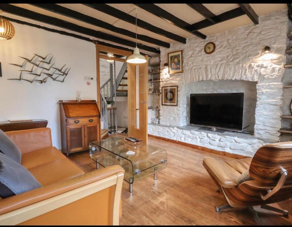 a living room with a couch and a stone fireplace at Coastal Village Cottage in Talacre