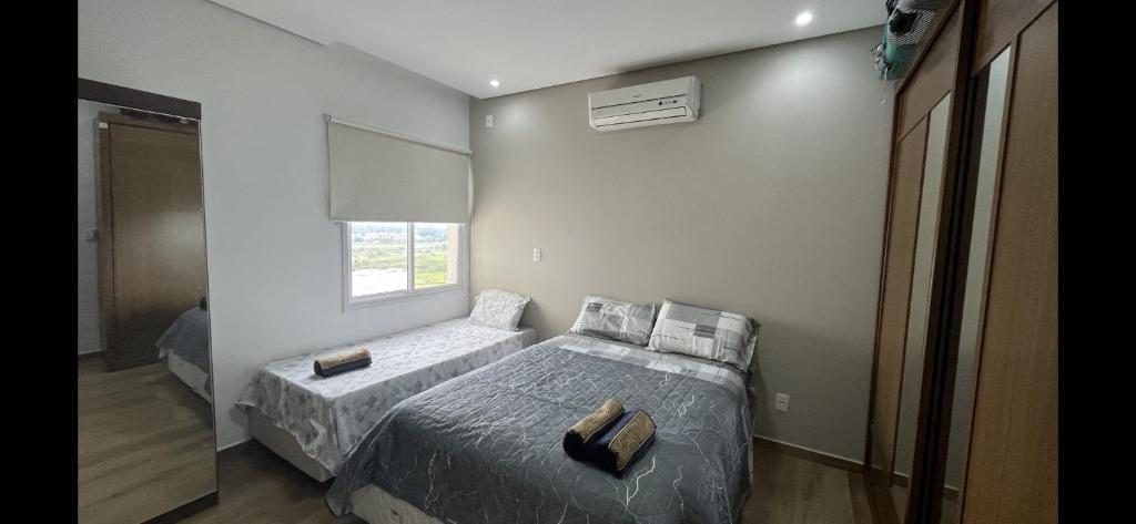1 dormitorio con 2 camas y ventana en Quartos privativos - Casa de alto padrão en Guaratinguetá