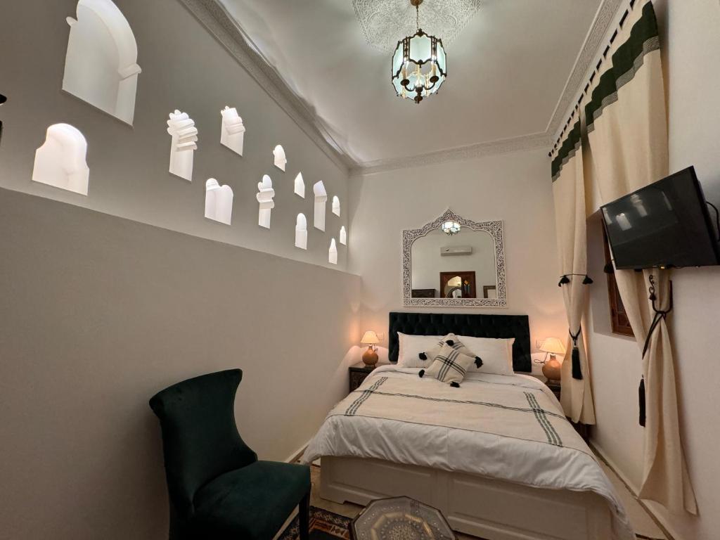 een slaapkamer met een bed, een spiegel en een stoel bij Riad Al-Qurtubi in Tanger