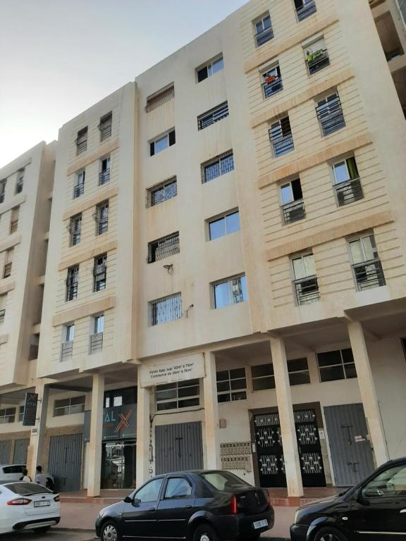 un grand bâtiment avec des voitures garées devant lui dans l'établissement Elhouda 56, à Agadir