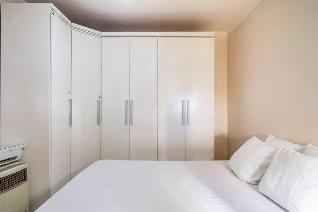 a white bedroom with a bed with white cabinets at Apartamento de um quarto, próximo ao Estadual. in Bauru