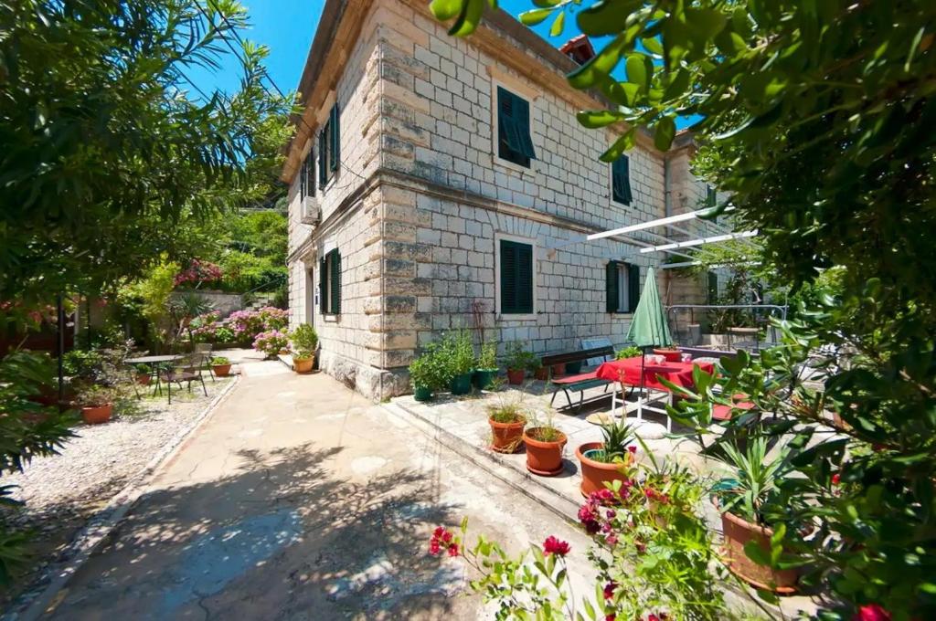 Apartments by the sea Dubrovnik - 20309 في دوبروفنيك: مبنى حجري مع فناء به طاولات ونباتات خزف