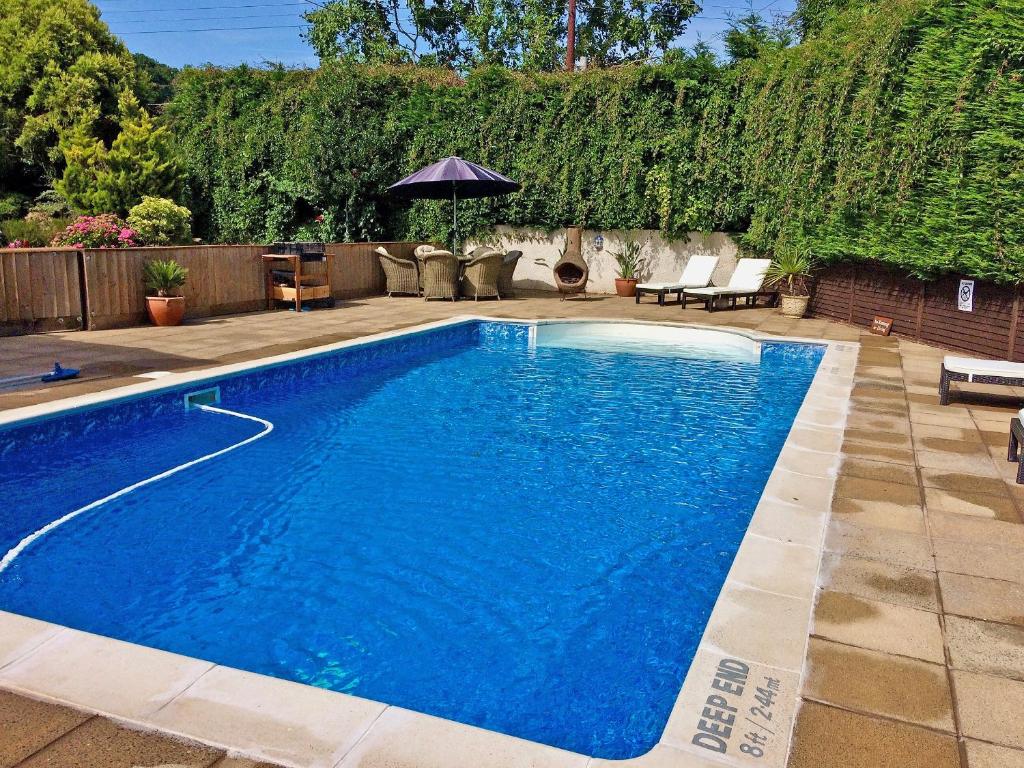 a swimming pool with blue water in a yard at Linnets in Fitzhead