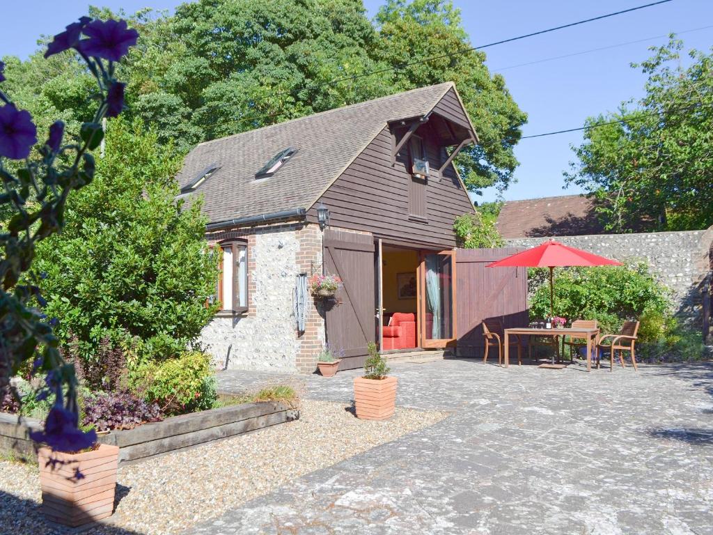 a cottage with a patio and a red umbrella at Darwin Cottage - E4509 in Jevington