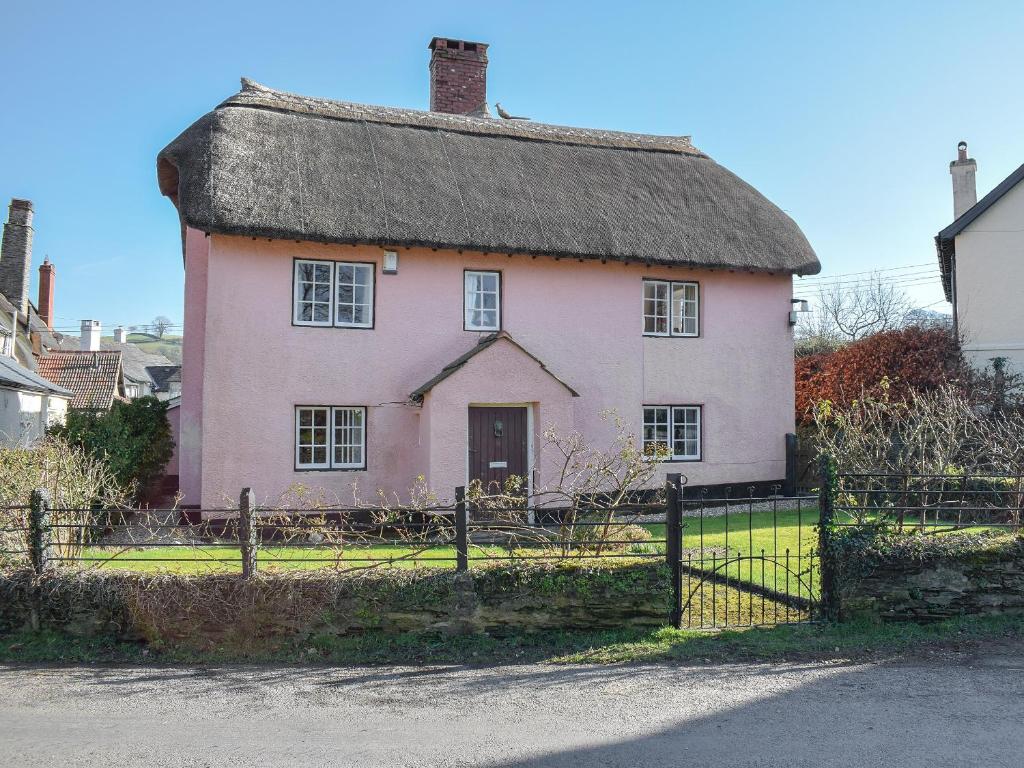 ein altes rosafarbenes Haus mit einem Strohdach in der Unterkunft Royal Oak Farm in Winsford