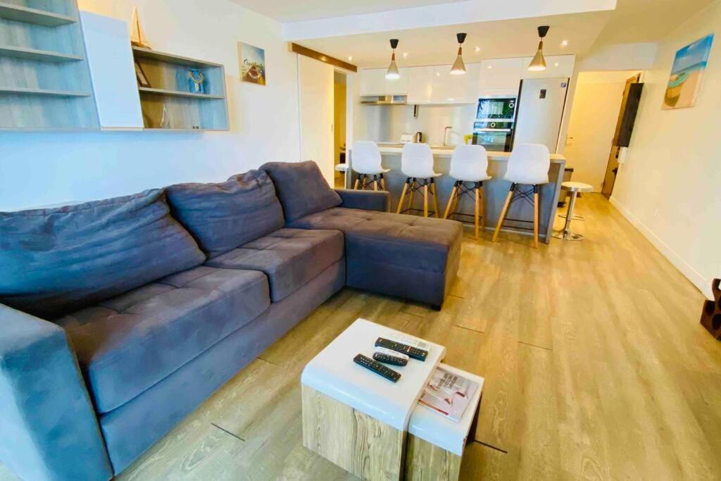 a living room with a blue couch and a table at Aux vents des rhums au cœur de la Marina du Gosier avec vue imprenable in Pointe-à-Pitre