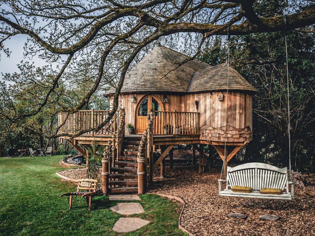 a tree house with a swing in a yard at Trewalter Treehouse in Brecon