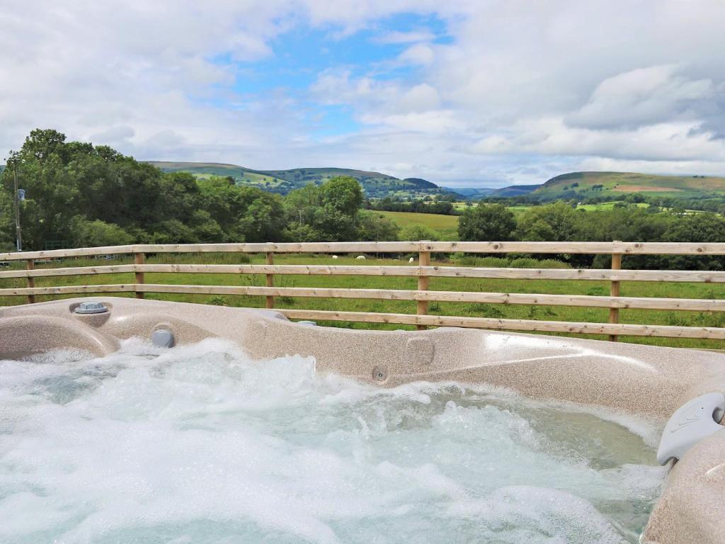 a hot tub with water in it next to a fence at Bryn Villa in Newbridge on Wye