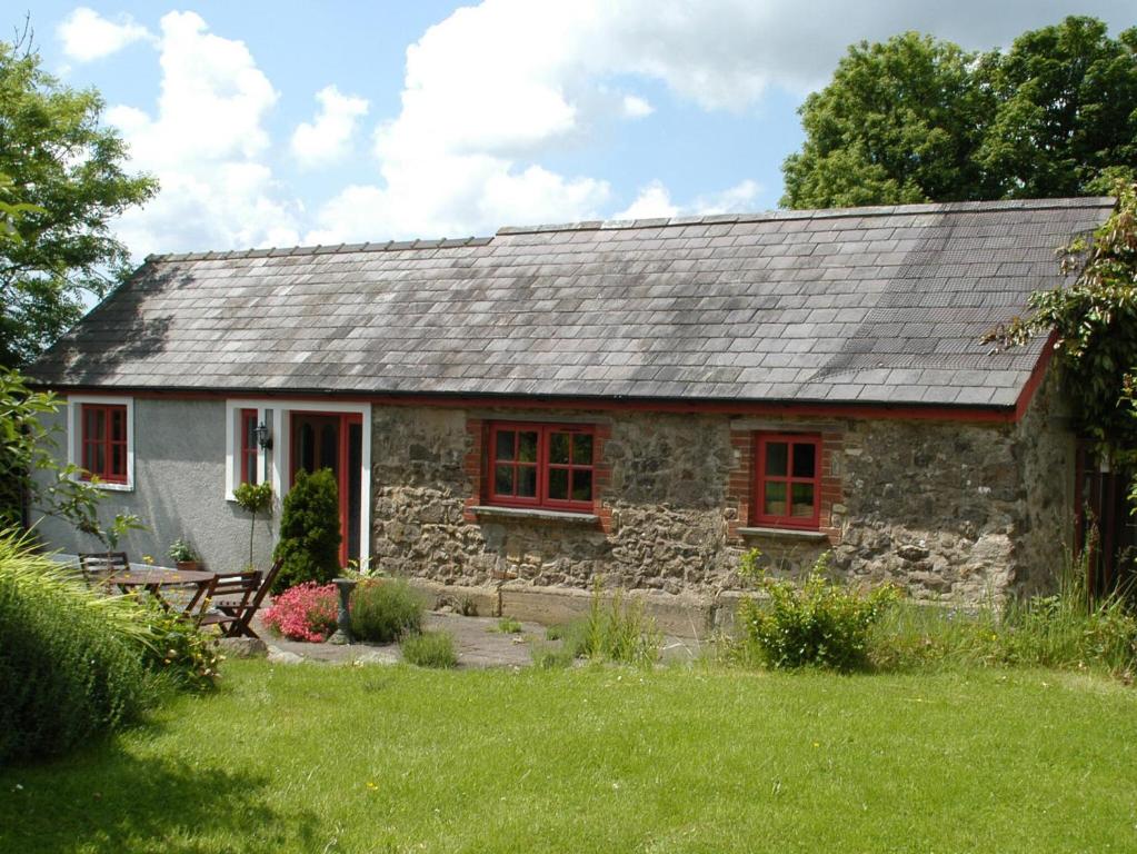 a stone cottage with red windows in a yard at Beats Cottage in Llangwm