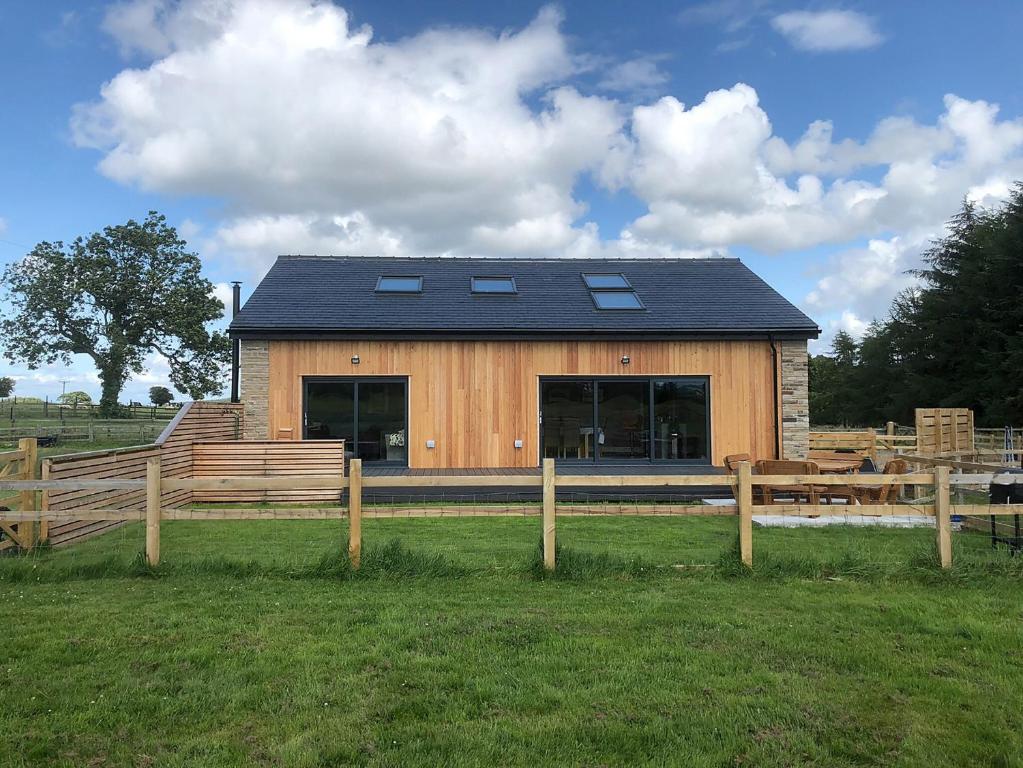 a wooden cabin with a fence in front of it at Brewers Cottage in Slaley