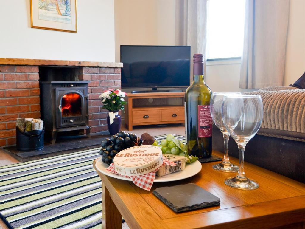 a living room with a table with a bottle of wine and wine glasses at Butterhole Cottage in Kelton
