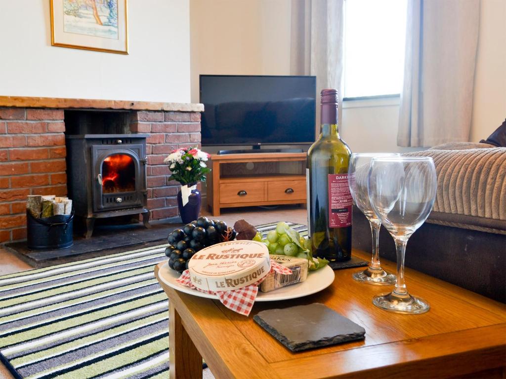 uma sala de estar com uma mesa com uma garrafa de vinho e copos de vinho em Butterhole Cottage em Kelton