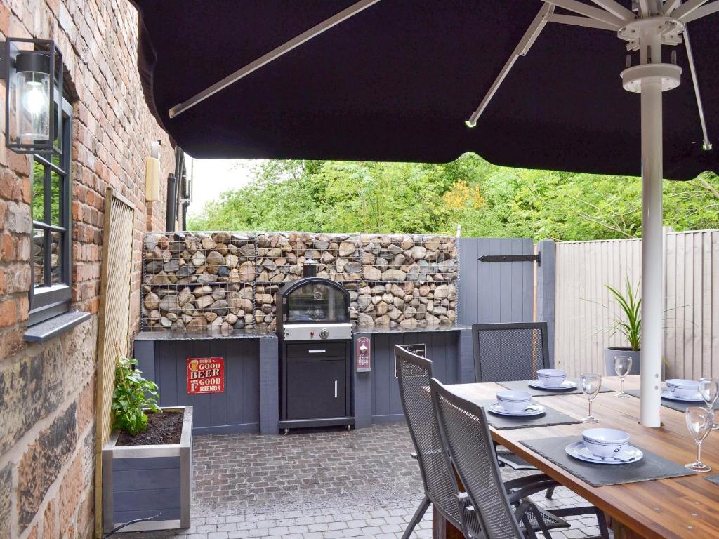 a patio with a table with chairs and an umbrella at Woodhouse View in Helsby