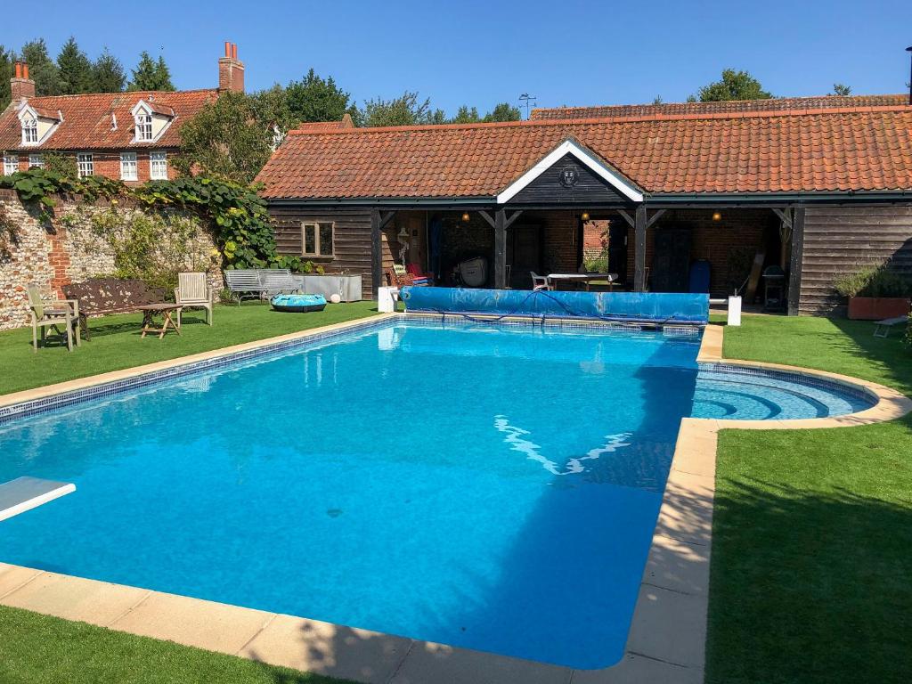 a large blue swimming pool in a yard at Orchard House in Baconsthorpe