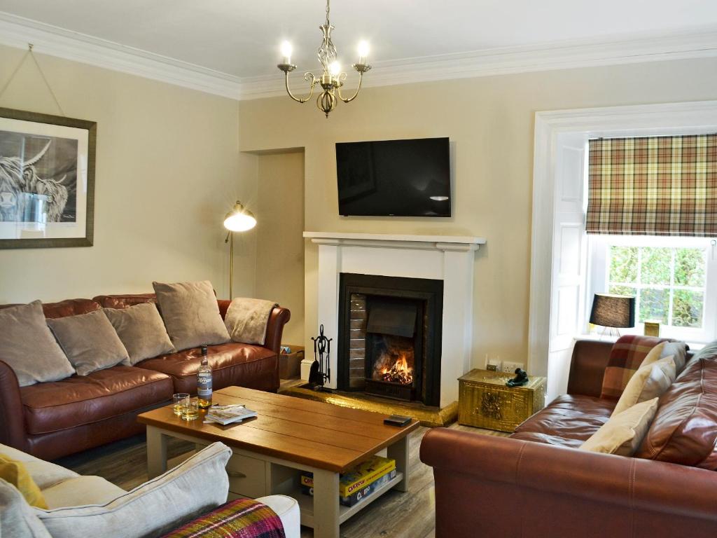 a living room with leather furniture and a fireplace at Altbeg in Brodick