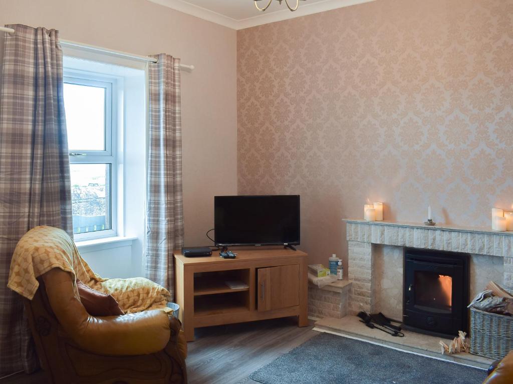 a living room with a tv and a fireplace at Ardlochan Cottage in Maidens