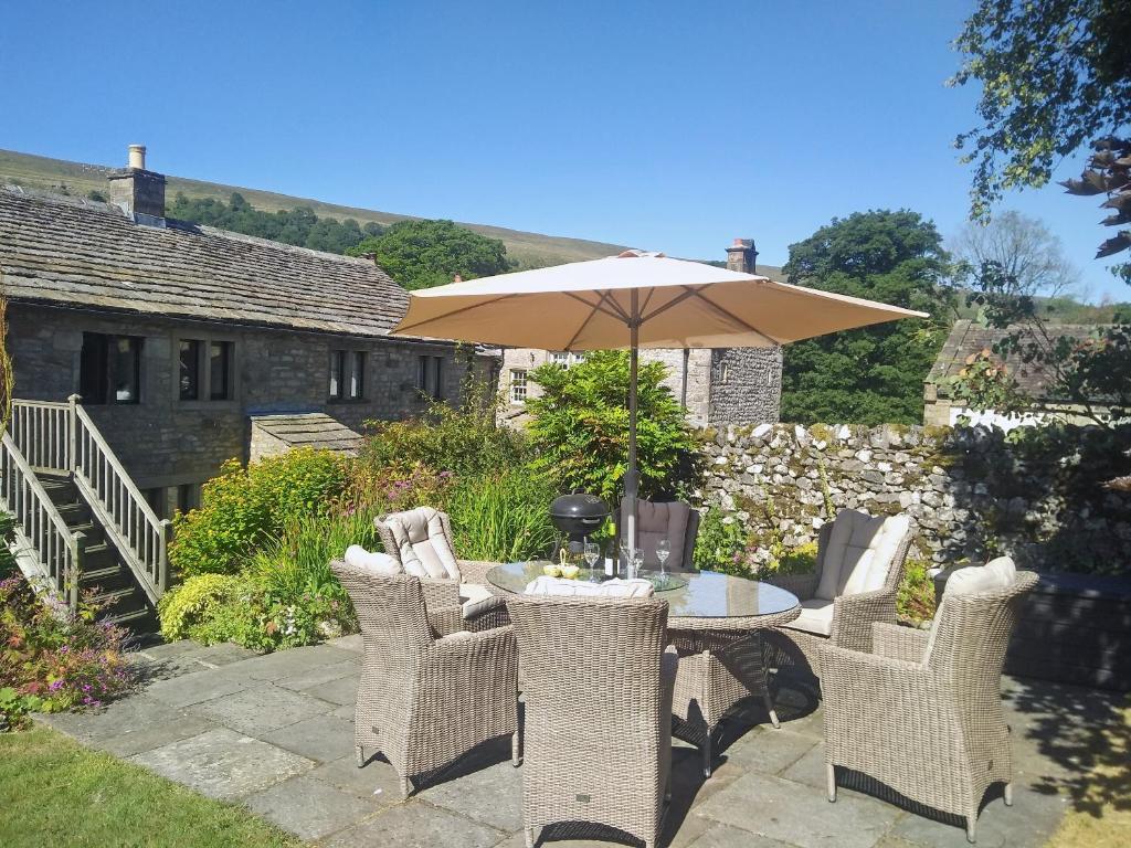 a table and chairs with an umbrella in a yard at Hilltop Barn in Starbotton