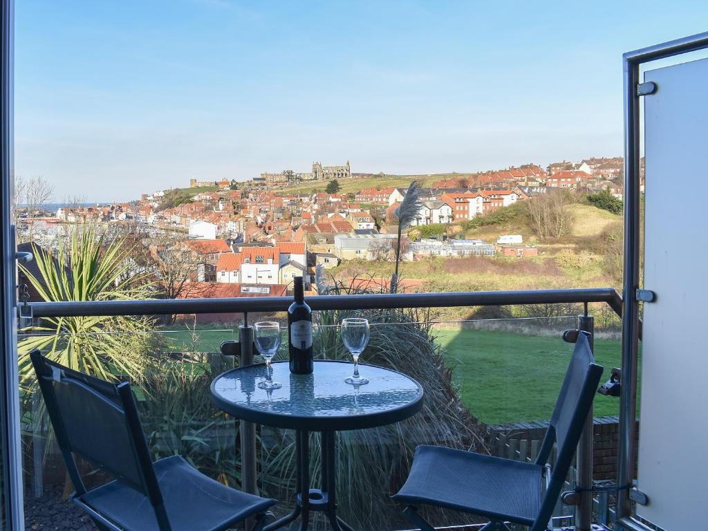 a table with two glasses of wine on a balcony at What A View! in Whitby
