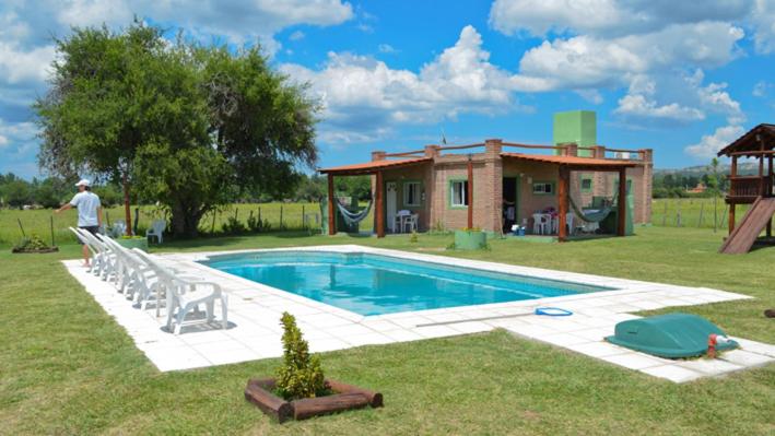 un hombre parado junto a una piscina al lado de una casa en Holiday Home Alta Vista en Mina Clavero