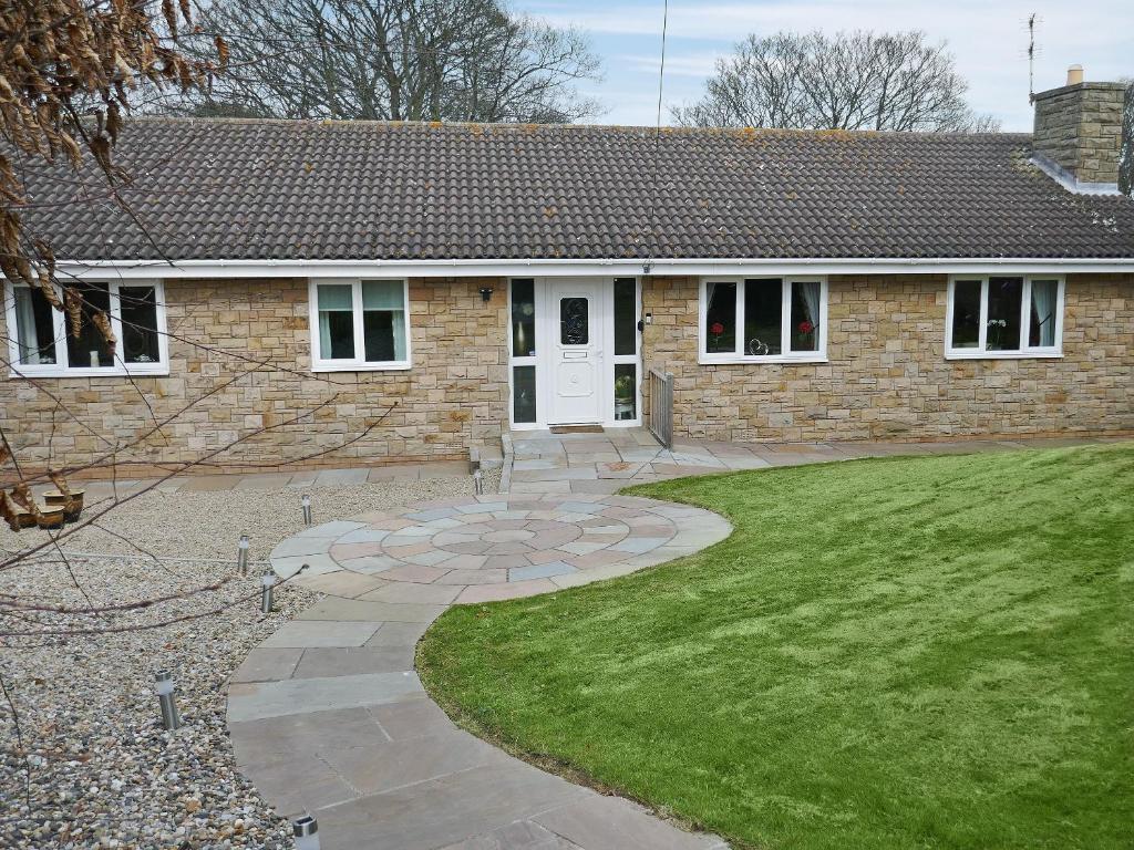 a brick house with a walkway in front of a yard at Kingfisher Cottage in Amble