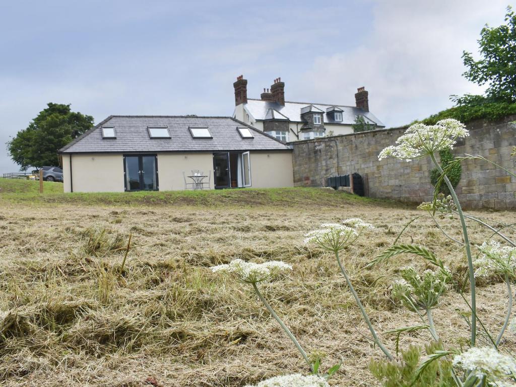 a house on a hill with a field in front of it at The Cottage At Stainsacre Hall in Hawsker