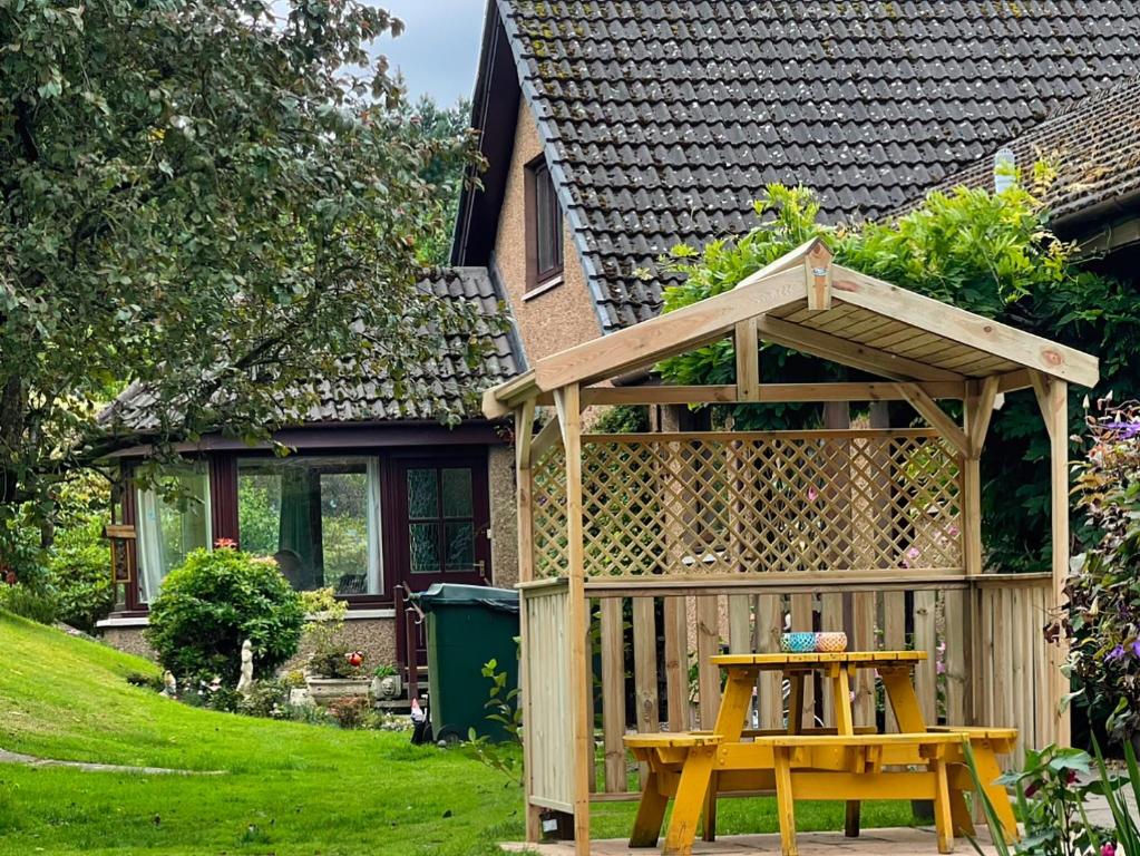 a wooden pergola and a table in front of a house at Drummond Neuk in Brackley