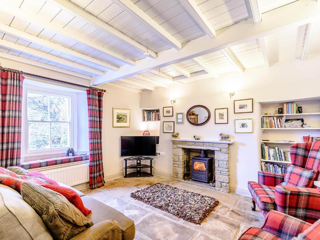 a living room with a fireplace and a tv at Ghyll View in Gunnerside