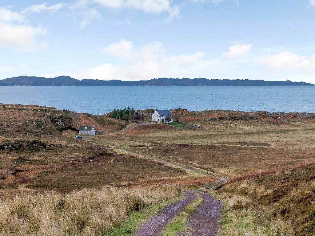 a dirt road leading to a house on a hill next to the water at Cliff Cottage in Kalnakill