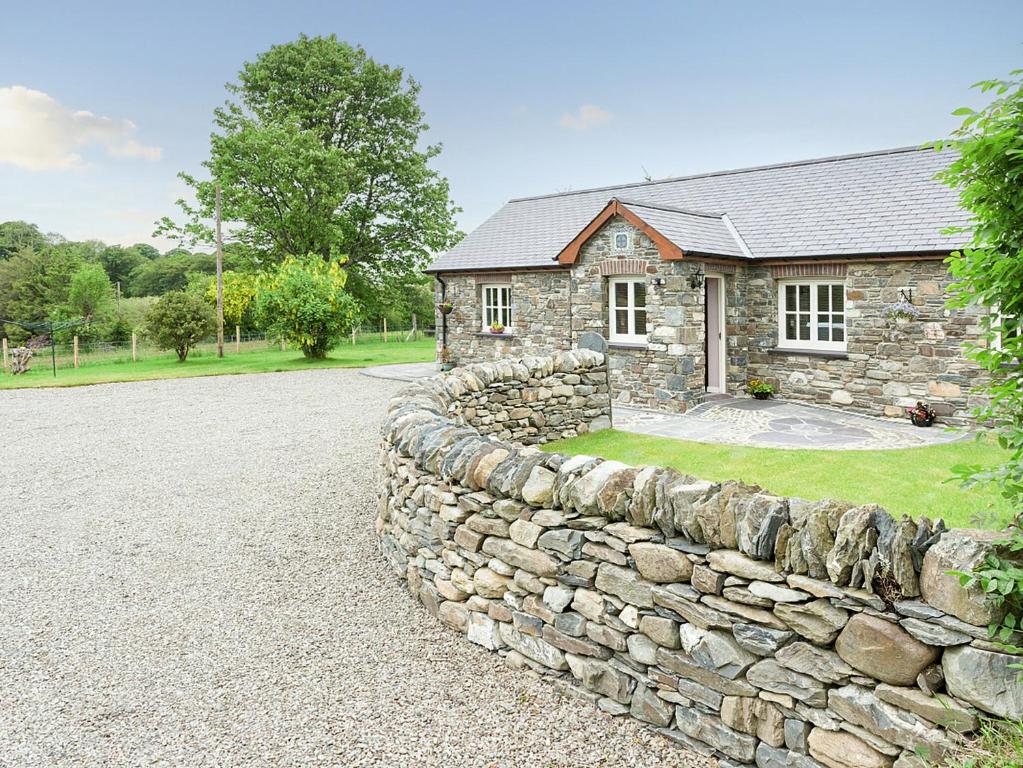 a stone wall in front of a stone house at Gelli Hir in Bronant