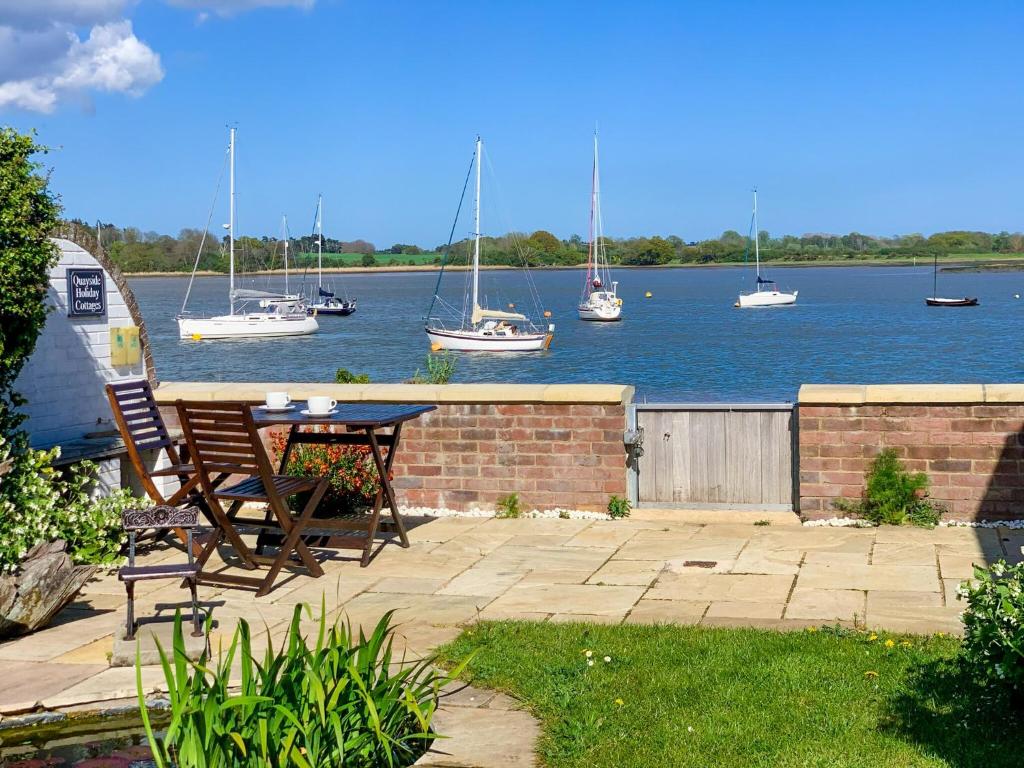 a patio with a table and boats in the water at The Boathouse Uk33900 in Waldringfield