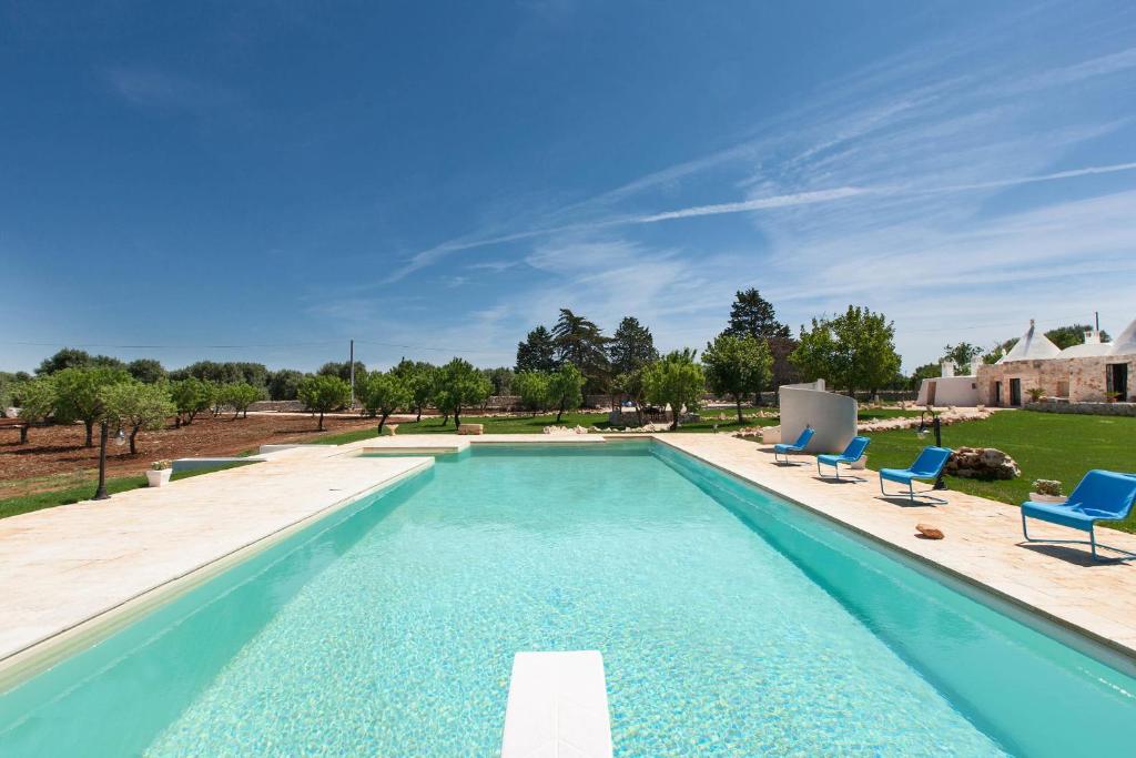 a swimming pool with two blue chairs next to a yard at Trullo Coco' by BarbarHouse in Ostuni