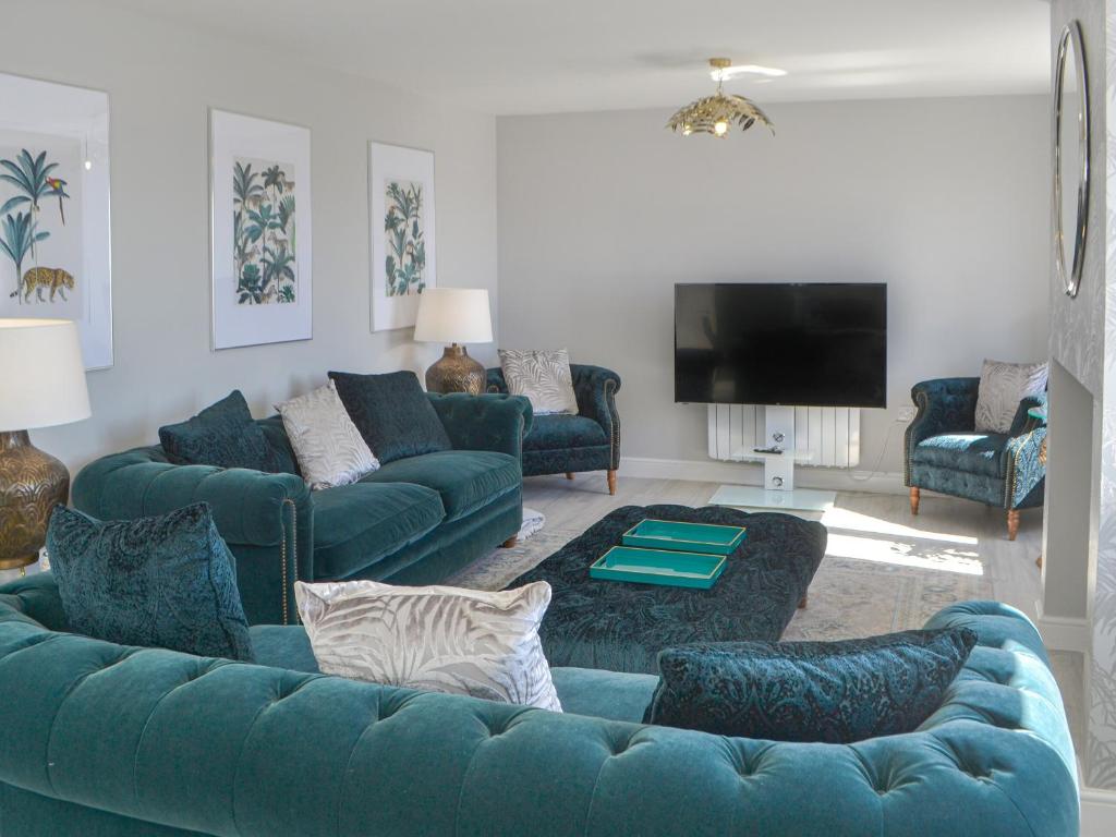 a living room with blue couches and a tv at Ladyburn House in Seahouses
