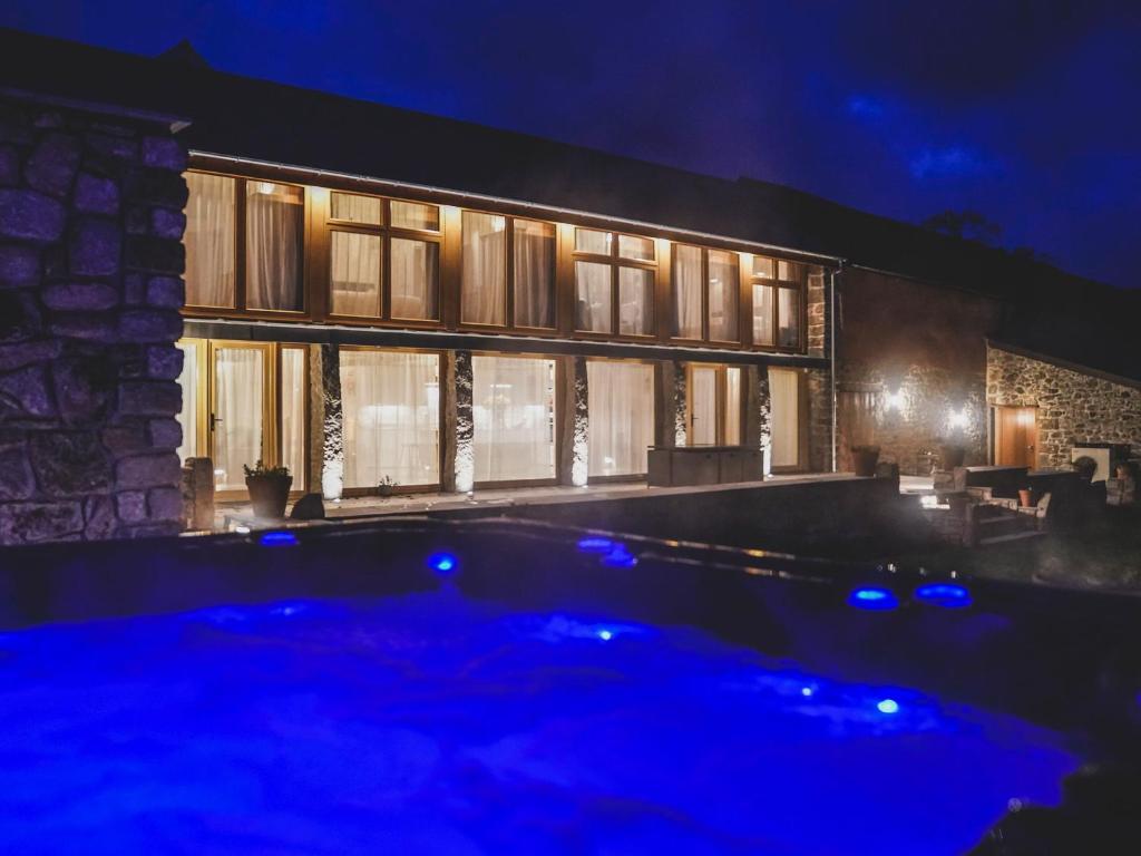 uma piscina em frente a uma casa à noite em Orchard Barn em South Tawton
