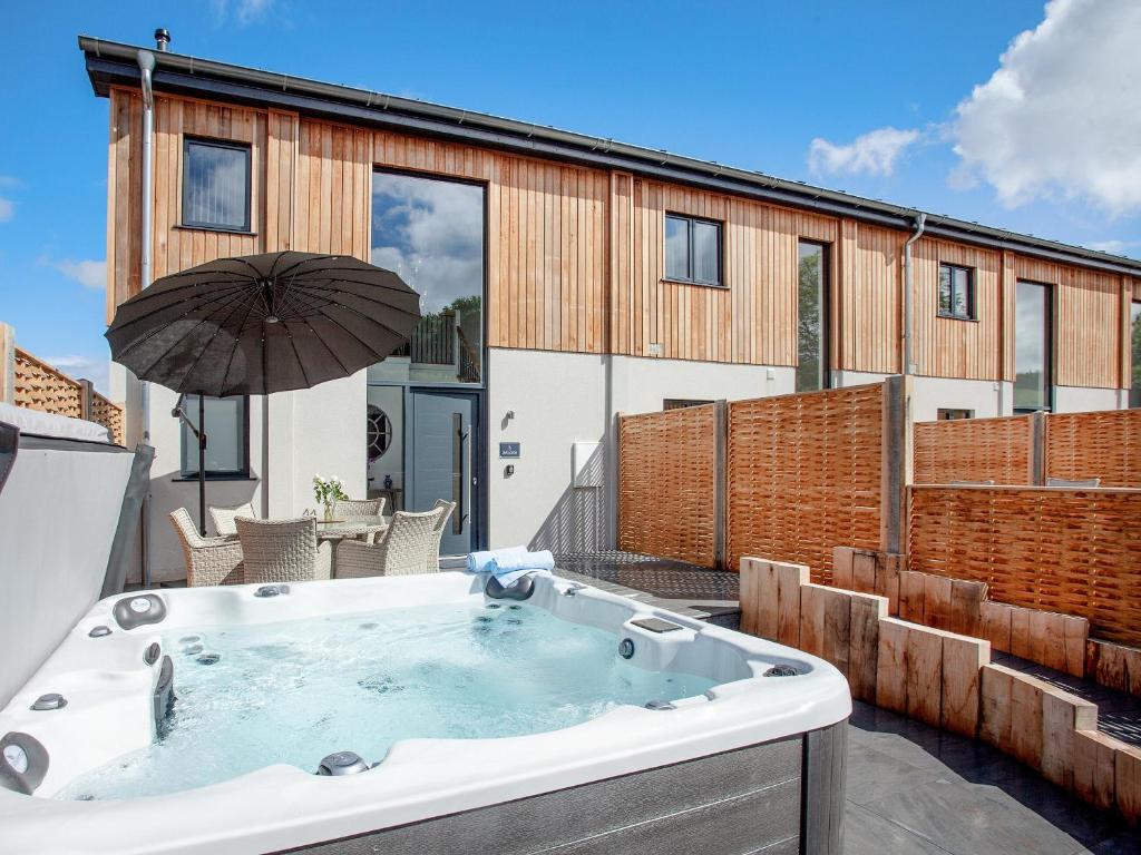 a hot tub on a patio with an umbrella at Bluebell-uk34613 in Nether Stowey