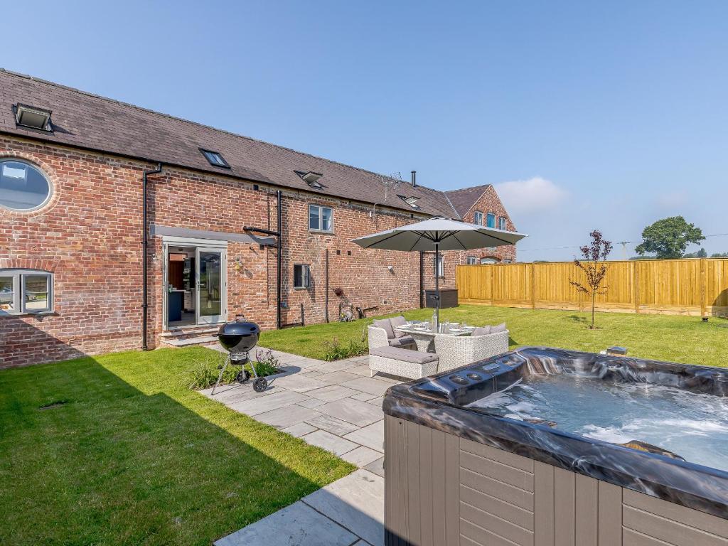 a backyard with a hot tub and an umbrella at The Hayloft - Uk34565 in Whitchurch