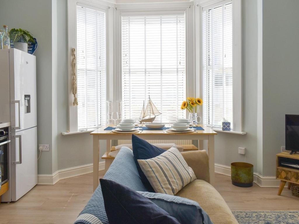 a living room with a couch and a table and windows at Sandgate Apartment in Sandgate