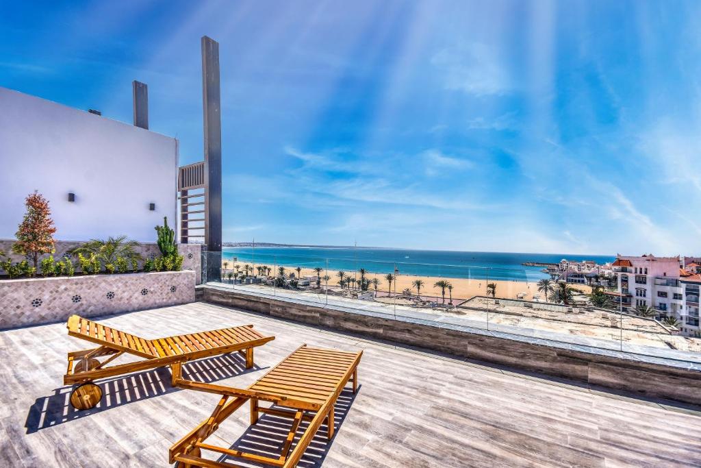 a pair of benches on a balcony overlooking the beach at Luxury Seafront Appartement 6-7p in Agadir