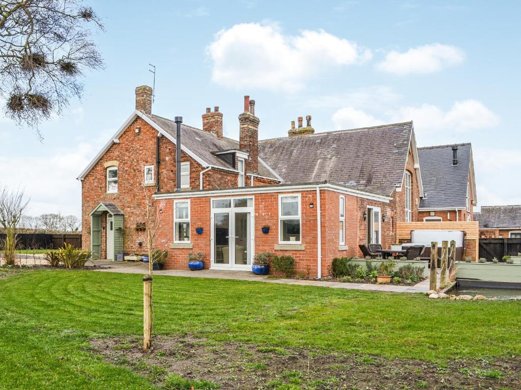 a brick house with a lawn in front of it at School Cottage in Lowthorpe
